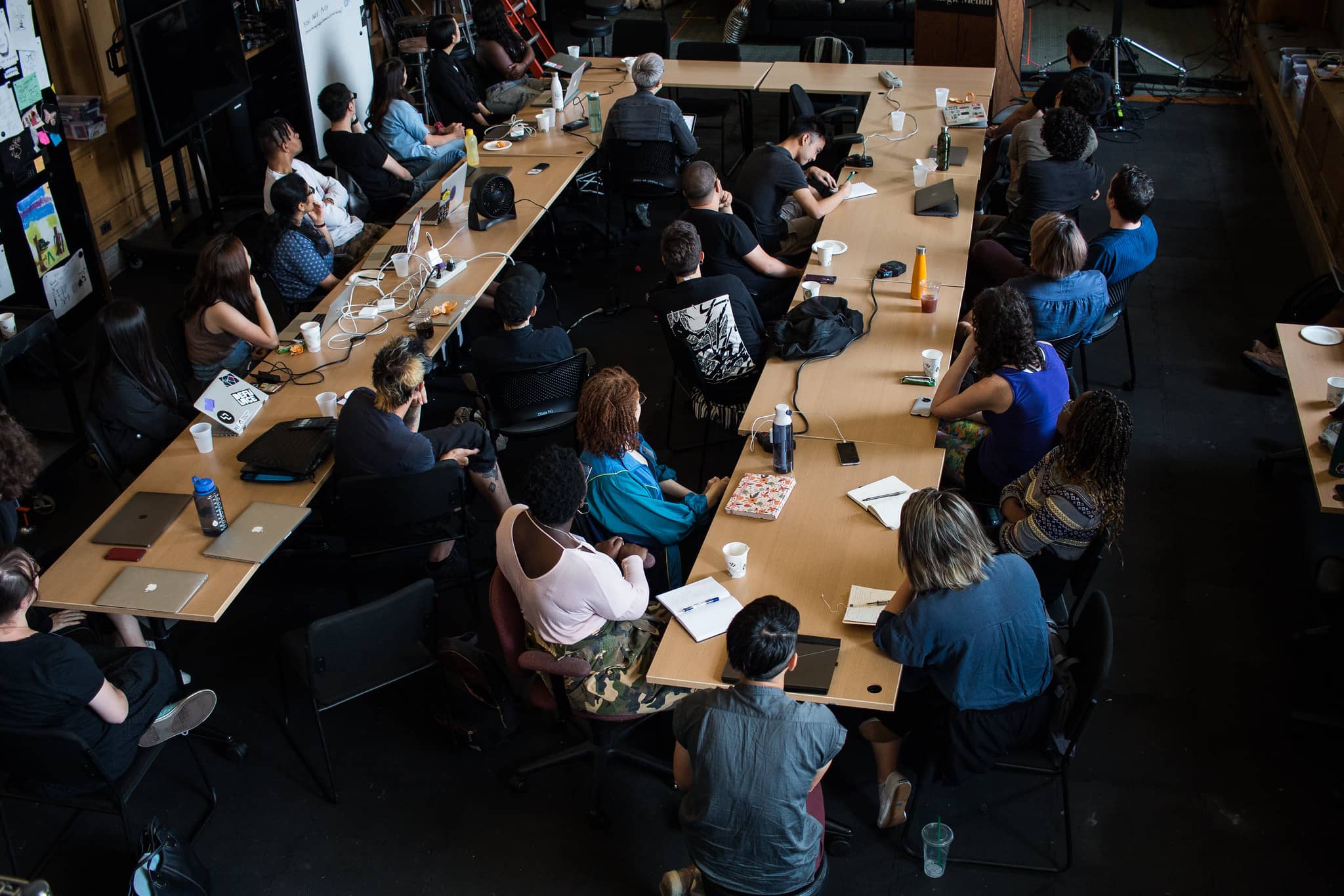 Participants sitting around a large U shaped table looking towards the front of the classroom"